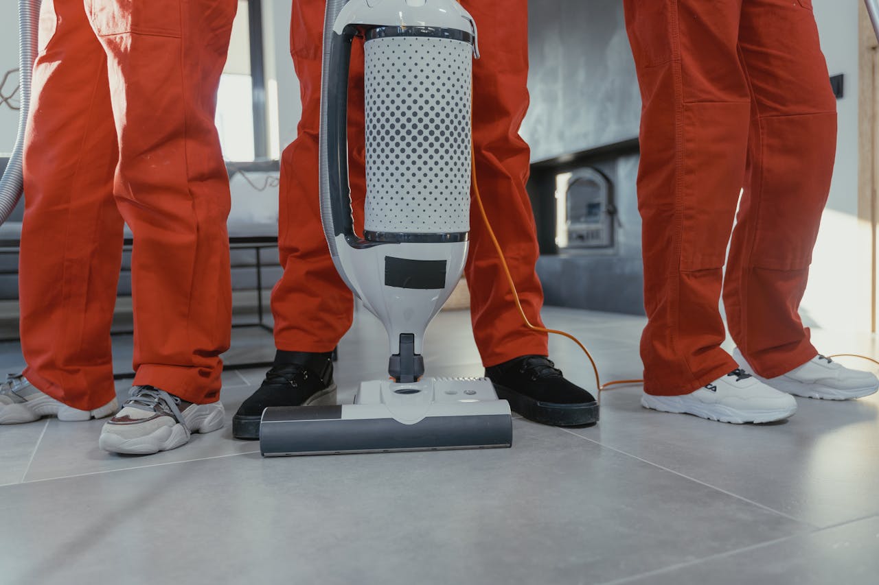 about-01 Team of professional cleaners in red uniforms using a vacuum cleaner indoors.